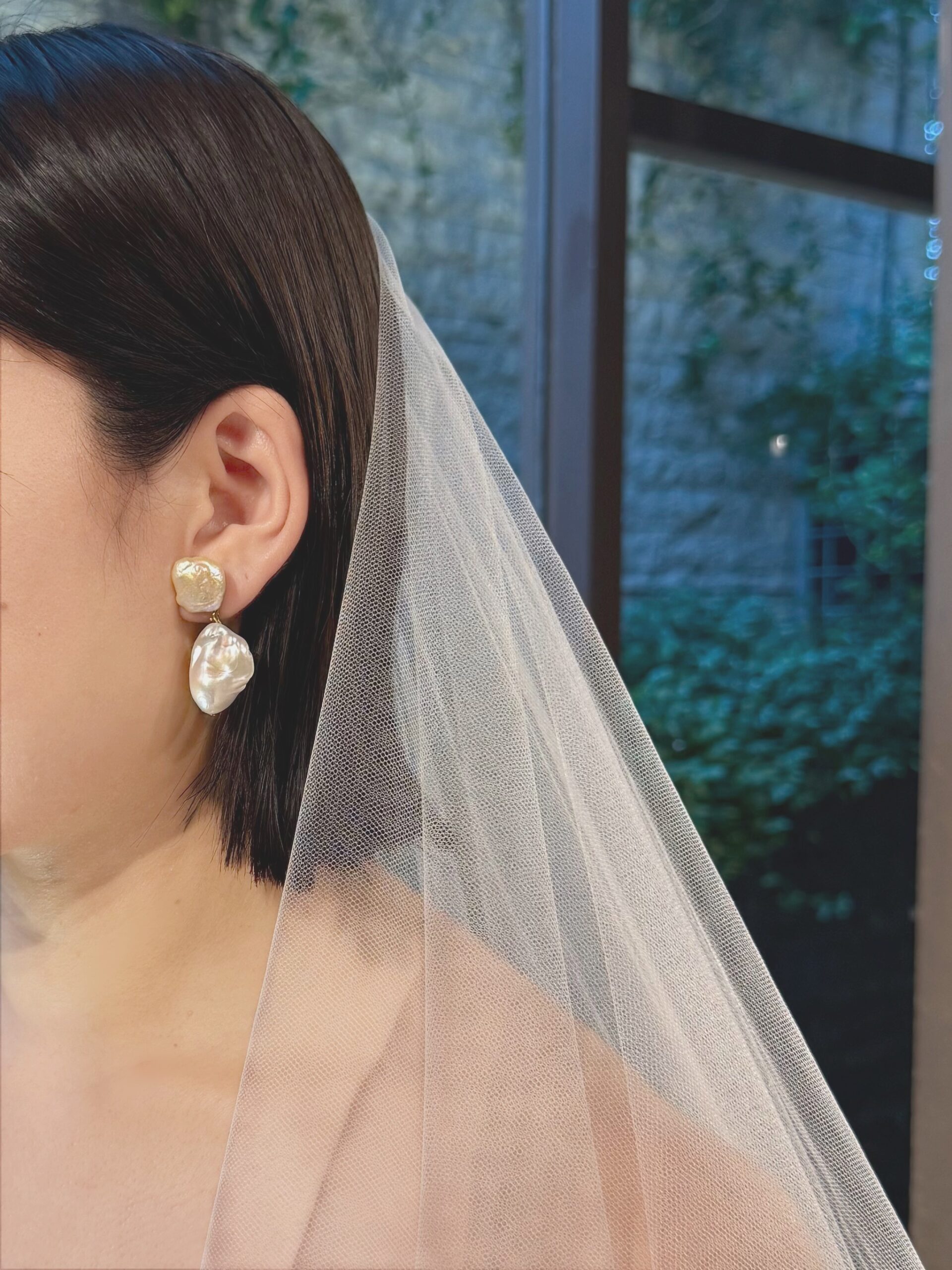 エナウラの新作ウェディングドレスに、パールのイヤリングを合わせることで凛とした女性を演出。