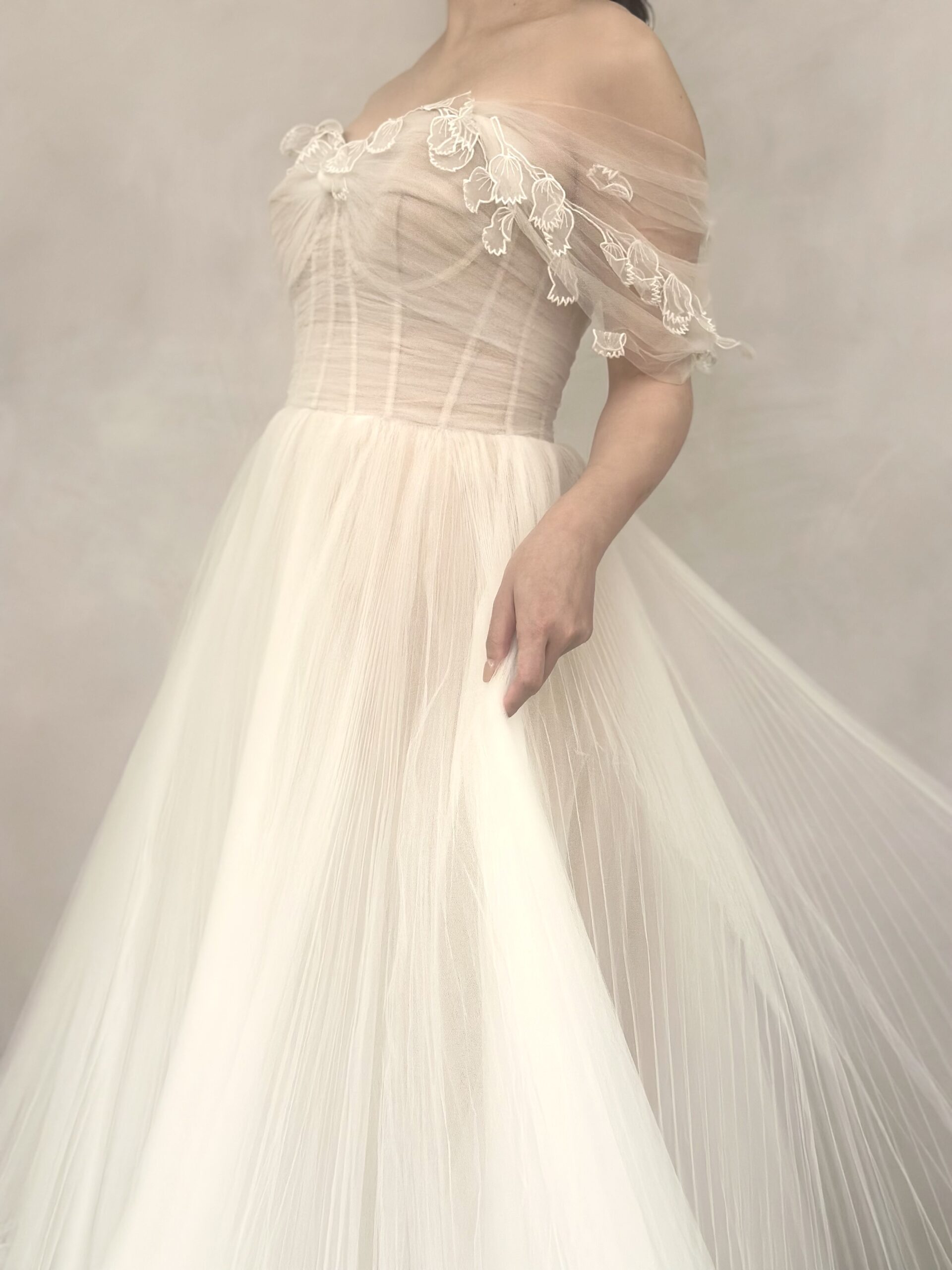 オフショルダーがそっと腕にかかり、動く度にプリーツのチュール素材が滑らかで上品な印象を与えます