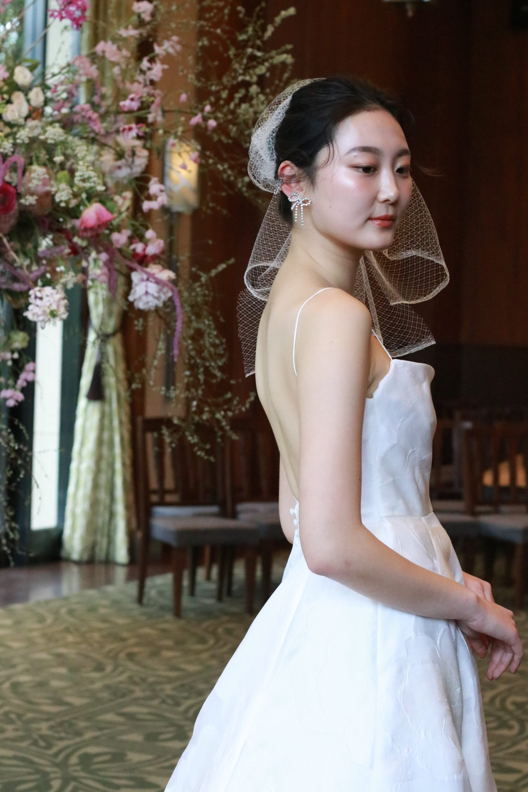 トレンドのリボンイヤリングを合わせた、ウェディングドレスはレラ ローズのもの