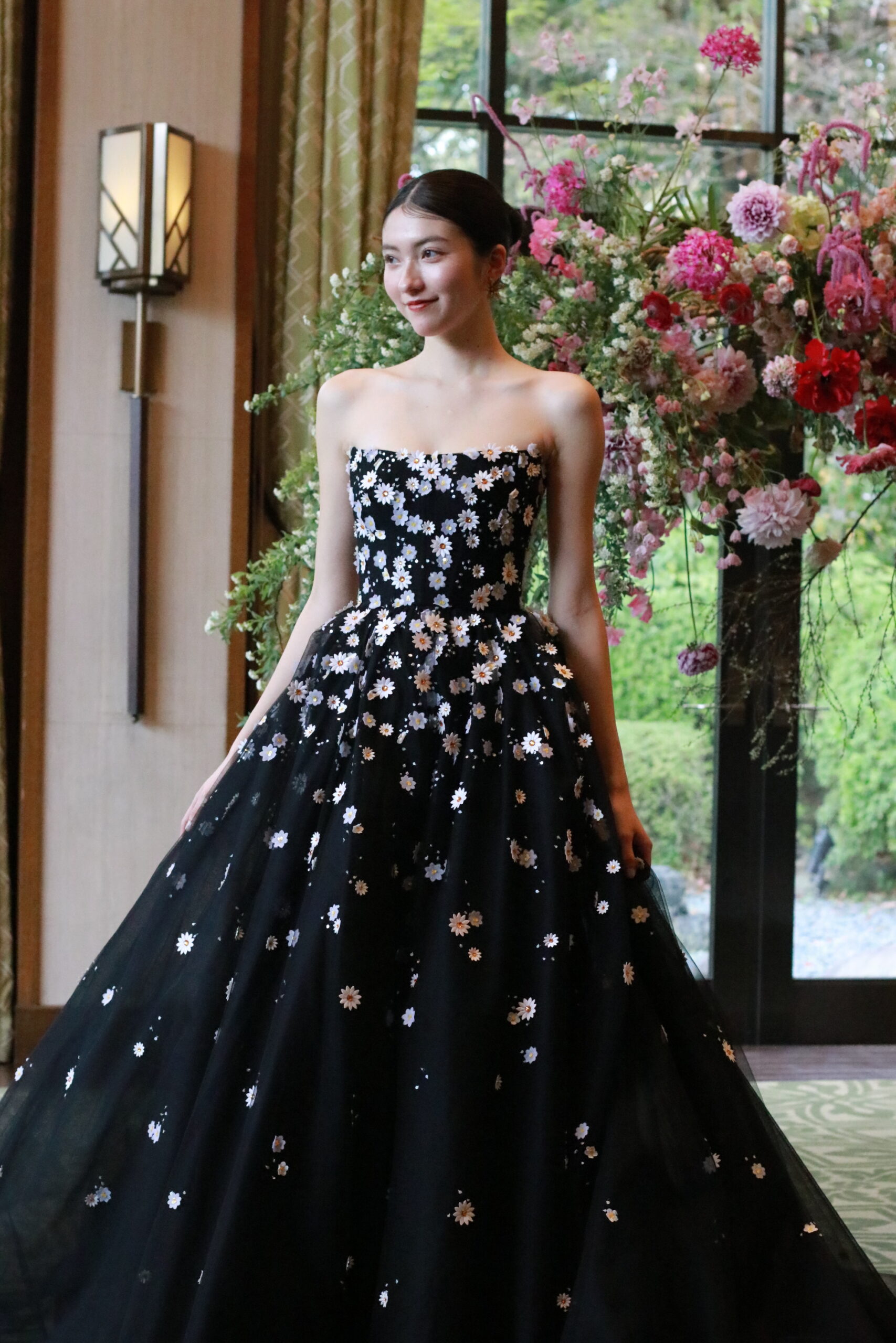 トレンドのブラックカラードレスは、モニークルイリエのもの。Aラインでデイジーのフラワーモチーフが愛らしい一着。