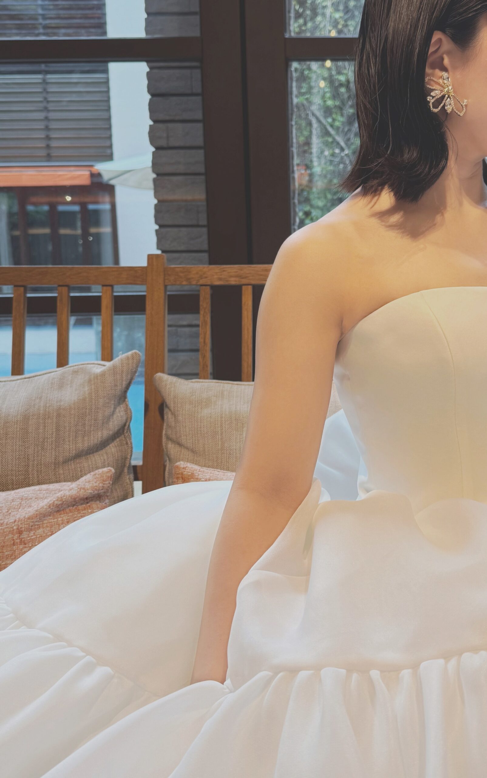 甘くなりすぎることなく可憐さとスタイリッシュさが兼ね揃えられたこちらのアムサーラの新作ウェディングドレスには、あえてイヤリングのみでまとめ、光を拾うゴールドのイヤリングがドレスのシルクホワイトの柔らかな色味を引き立てます。