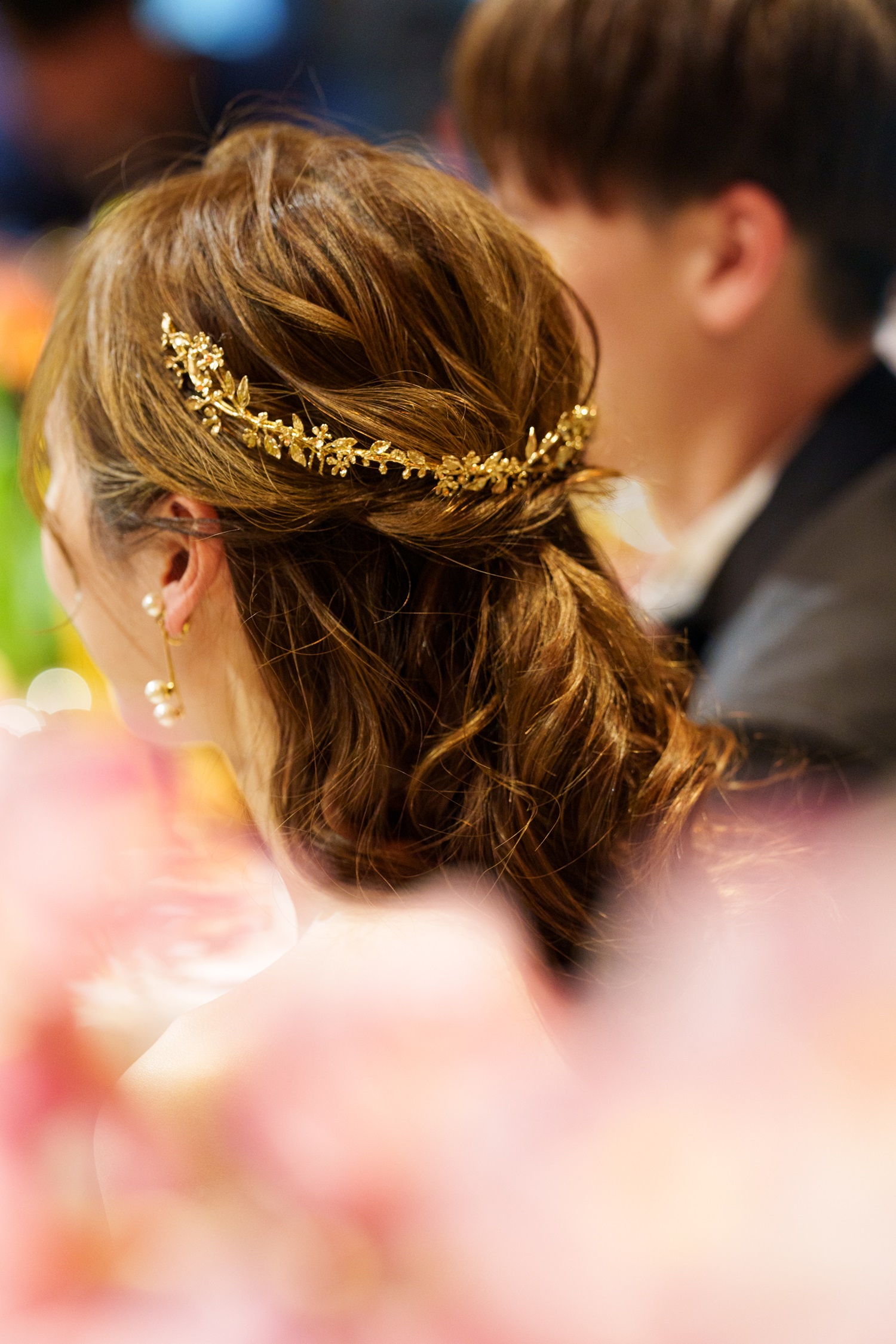 トレンドのヘアスタイルであるダウンヘアにパールモチーフのイヤリングとゴールドのバックカチューシャを合わせたおしゃれなスタイリング