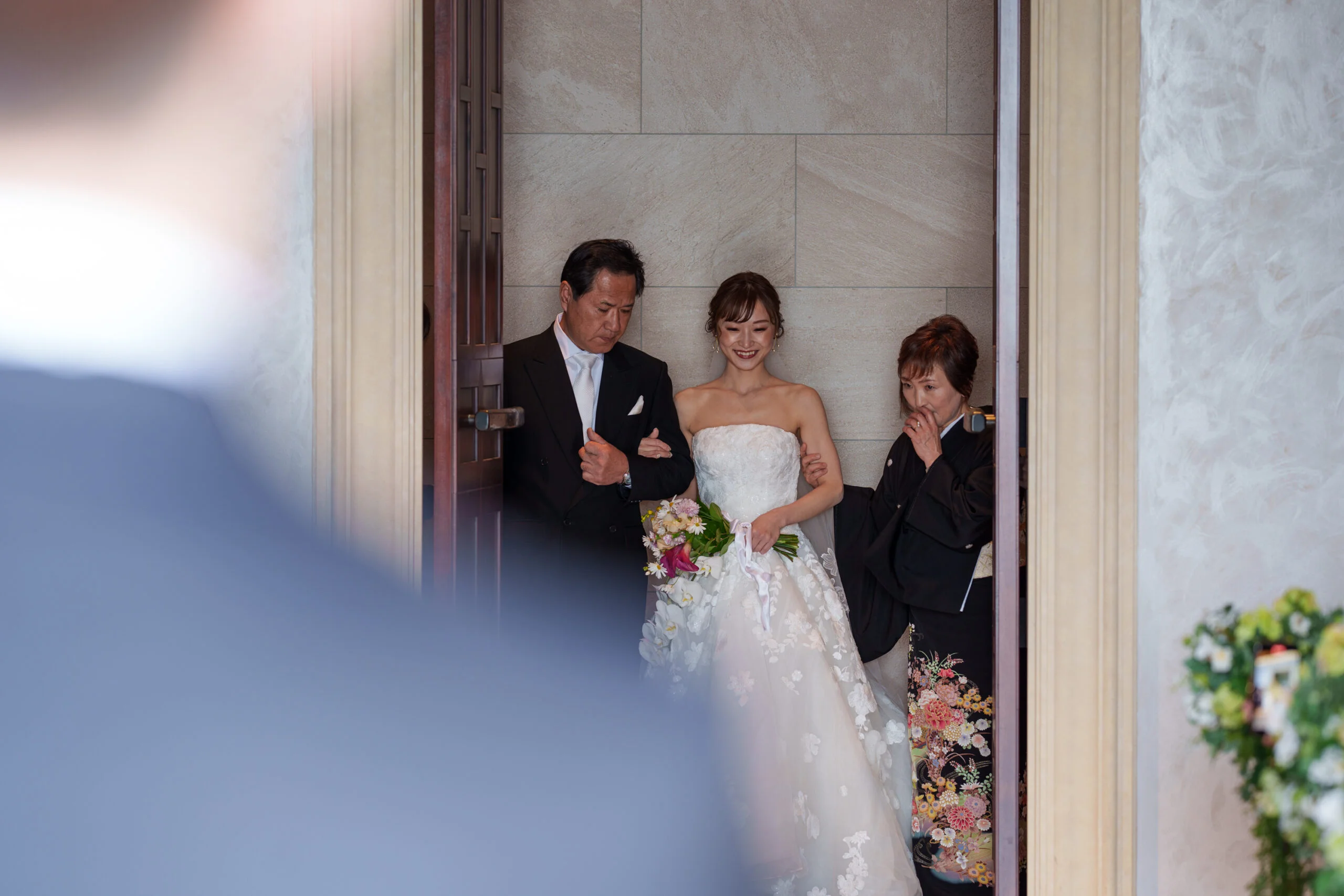 モーニングと黒留袖の正装を纏ったご両親様と一緒に登場する、ザ ルイガンズでの結婚式の挙式の始まりのシーン